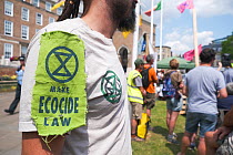 Extinction Rebellion protester wearing logo and &#39;Make Ecocide Law&#39; message. Climate change rally, Bristol, England, UK. 16 July 2019.