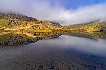 Reflections in Lake Cwmorthin showing pieces of slate from the slate mine below the surface near Blaenau Ffestiniog, North Wales, UK, April 2018.