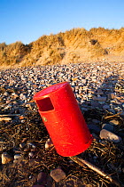 Red litter bin on Rhosilli Beach, Gower, South Wales, UK, March.