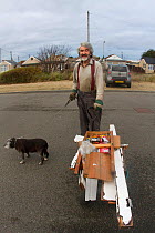 Kevin Whales picking up litter with home made cart whilst taking dog for a walk. Jaywick, Essex, England, UK, December.