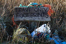 &#39;Leave only footprints&#39; sign with rubbish collected by volunteers from Rhosilli beach, Gower, South Wales, UK. March 2019.