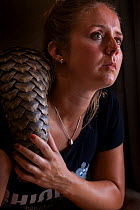 Young orphaned Temminck&#39;s ground pangolin (Smutsia temminckii) rests on the shoulder of vet and pangolin foster mother Jade Aldridge at the Rhino Revolution rehabilitation facility in South Africa...