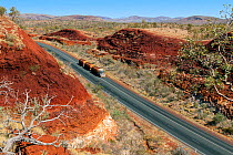 Road running through Munjina Gorgewith vehicle hauling tanks. Karijini National Park, north west, Western Australia, May 2010
