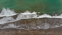 Aerial tracking shot of waves breaking on a sandy beach, Tochigue, Esmeraldas Province, Ecuador, 2018. (non-ex)