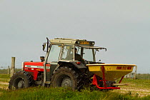 Tractor spreading fertilizer on machair to improve it for agricultural production by crofters, North Uist, Scotland, UK, June.