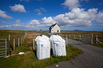 Nitrogen fertilzer in bags, ready for application to machair, coastal grazing habitat. Outer Hebrides. Scotland, UK, June.