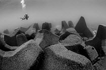 Diver close to wave breaker concrete blocks, Xiaoliuqiu Island, Taiwan
