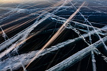 Snow blowing in wind, over cracks in the clear ice of Lake Baikal. Siberia, Russia. February.