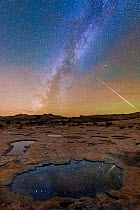 Eroded &#39;Pot Holes&#39; full of rain water at night with the Milky-way and shooting star , Bears Ears National Monument, Echo Mesa, Utah. USA. November 2018.