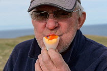 Man eating boiled Common murre / guillemot (Uria aalge) egg, portrait. Langanes Peninsula, Iceland. May 2018.