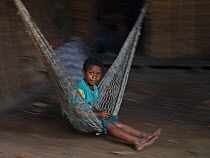 Boy swinging on hammock. Nara village, Makira Island, Solomon Islands. 2018.