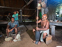 Chief of Nara village and some family members making traditional Taro pudding. In chiefs house, Makira Island, Solomon Islands. 2018.