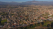 Aerial panning shot looking over Sangolqui, a suburb of Quito, with many volcanoes visible in background, including snowcapped Cotopaxi, Ecuador, 2018. (non-ex)