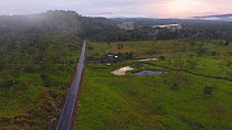 Aerial shot at dusk of a cattle farm cut out of the Amazon rainforest, a road has brought colonists and land speculators into this area which previously was primary rainforest, with the Rio Napo in th...