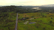 Aerial shot at dusk of a cattle farm cut out of the Amazon rainforest, a road has brought colonists and land speculators into this area which previously was primary rainforest, with the Rio Napo in th...