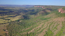 Drone shot tracking over cerrado grassland and cattle ranch landscape, with tall mountains and cliffs, Matto Grosso, Brazil, 2019.