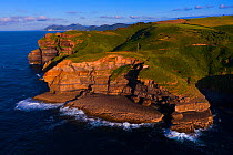 Cliffs of Arnuero above Cantabrian Sea in evening light, aerial view. Transmiera Ecopark, Santona, Victoria and Joyel Marshes Nature Reserve, Cantabria, Spain. June 2019.