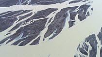 Aerial tracking shot of a glacial river flowing through a plain of black sand, Iceland, August 2018.