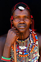 Maasai man adorned with traditional bead work and colour glass pearls around his neck, head portrait. Masai Mara National Reserve, Kenya.