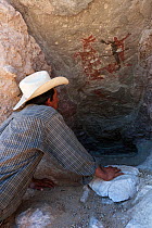 Guide looking at prehistoric rock painting. El Palmarito cave, Santa Martha Sierra, El Vizcaino Biosphere Reserve, Baja California Peninsula, Mexico. 2008.