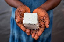 Congolese woman holding hand made palm oil soap, made by local women to sell at the market. Oshwe, Democratic Republic of Congo. May 2017.