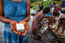 Congolese woman holding hand made palm oil soap, made by local women to sell at the market.  Oshwe, Democratic Republic of Congo. May 2017.