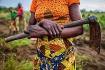 Sala Ozwa, a women's association, holds an axe which she uses to cultivate a shared field in the village of Mbanzi. Democratic Republic of Congo. May 2017.