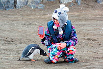 Chinese tourist from Antarctic expedition cruise ship taking selfie with Gentoo penguin (Pygoscelis papua) that has walked up to her. Antarctic Peninsula, Antarctica. February 2019.
