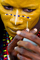 Man from Wodaabe ethnic group painting face for Gerewol gathering of different clans in which women choose a husband. Men dress in best clothes and ornaments and sing and parade in front of the young...