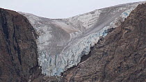 Retreating glacier, shot tilts down from glacier tongue to waterfall to dry valley, Greenland, 2016.