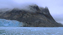 Wide-angle shot tilting up from brash ice to glacier and mountain, Magdalena Fjord, Svalbard, Norway, 2016.