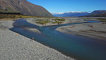 Aerial tracking shot of Rakaia river, with a man fishing, Canterbury region, New Zealand, 2017.