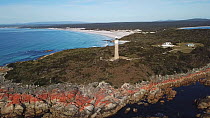 Aerial tracking shot up from details of coastal rocks to Eddystone Point Lighthouse, Tasmania, Australia, 2018.