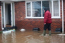 Resident walking in flooded area outside his home showing sandbags to try and keep water from entering his home, and water damage to the walls, Fishlake, South Yorkshire, UK. November 2019.
