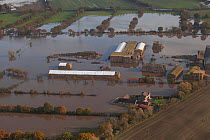 Aerial view of a flooded farm with straw bales covered with white sheeting, surrounded by fuel oil in the water, Fishlake, South Yorkshire, UK. November 2019.