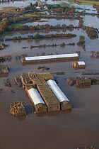 Aerial view of a flooded farm with straw bales covered with white sheeting, surrounded by fuel oil in the water, Fishlake, South Yorkshire, UK. November 2019.
