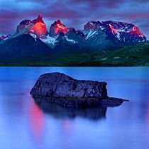 Central Massif and towers of Torres del Paine National Park at sunrise, island reflected in Lago Pehoe in foreground. Patagonia, Chile. November 2018.