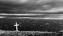 Stormy seas and cross on a grave. In background is the Malmey island. Iceland 2016