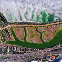 Coloured water leaking from photogypsum storage pond creates tidal channels in saltmarsh habitat. Huelva, Southern Spain. Railway lines pass nearby. Phosphogypsum is a radioactive by-product in the ma...