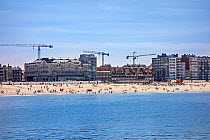 Tourists on the beach and flats and apartments being built at Nieuport / Nieuwpoort, seaside resort along the North Sea coast, West Flanders, Belgium 2019