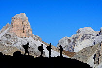 Four mountain climbers silhouetted against Torre dei Scarperi / Schwabenalpenkopf, Sexten Dolomites, Parco Naturale Tre Cime, South Tyrol, Italy, October 2019