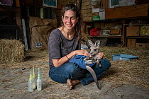 Rena Gaborov feeding some of her eastern grey kangaroo (Macropus giganteus) orphans in her mother's shed. Rena and her partner Joseph had to evacuate their wildlife (wombats, possums and kangaroos) fr...
