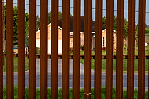 House viewed through border wall. Southmost Preserve, Nature Conservancy Reserve, Brownsville, Texas, USA. 2019.
