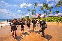 Scuba diving instructor Anthony Manion on his way to the ocean with four students in front of the Grand Wailea Hotel on Maui, Hawaii. July 2019. Model released.
