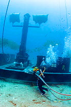 Commercial hard hat diver wearing normal (non-wetsuit) clothing hauling hydraulic lines for a winch on the anchor device for a massive wave energy buoy off Kaneoho Bay, Oahu. The 40-kW experimental bu...