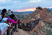 Tourists photographing Rainbow Mountains at sunset. Zhangye National Geopark, China Danxia UNESCO World Heritage Site, Gansu Province, China. 2018.
