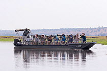 Wildlife photographers taking photos from boat on Chobe River. Chobe National Park, Botswana.