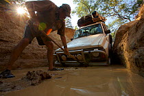 Man working to dig out the Nissan stuck at the bottom of the drop into Palm Creek on the OTL, Cape York Peninsula, Queensland, Australia.