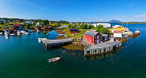 Aerial view of an island far out in the sea in Norway&#39;s widest strandflat. Fishing village with boats and boat houses. Husvaer, Helgeland Archipelago, Norway. July.