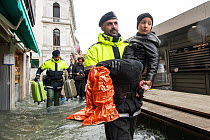 Venetian police carrying boy through flooding in Venice, Italy, December 2019.